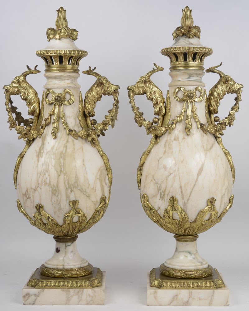 Een paar cassolettes van beige marmer, versierd met guirlandes, strikken, bokkenkoppen en bloemen van verguld brons. XIXe eeuw.