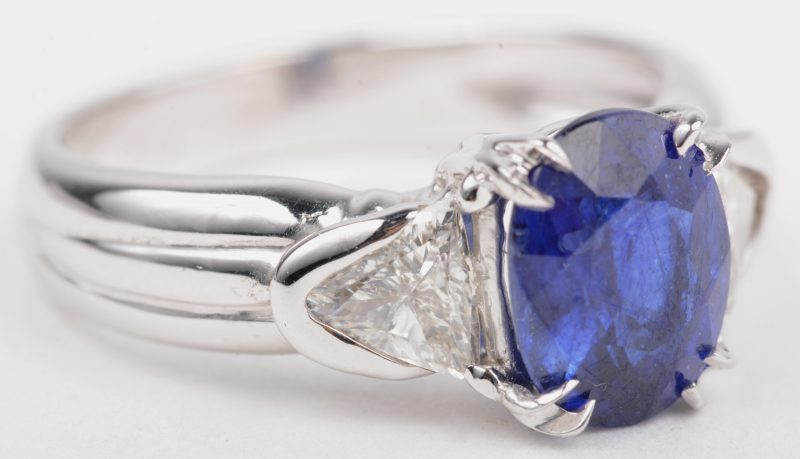 Een 18 K witgouden ring bezet met een saffier van +- 2,35 ct. en twee diamant princesses met een gezamenlijk gewicht van +- 0,50 ct.