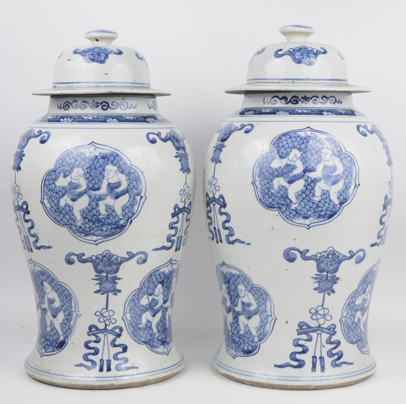 Een paar dekselvazen van Chinees porselein met een blauw op wit decor van personages in uitsparingen.