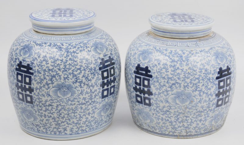 Een paar gemberpotten van Chinees porselein met een blauw op wit decor met langlevenstekens op florale achtergrond.