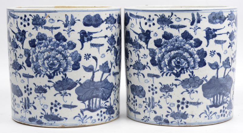 Een paar cilinderpotten van Chinees porselein met een blauw op wit decor van bloemen en planten.
