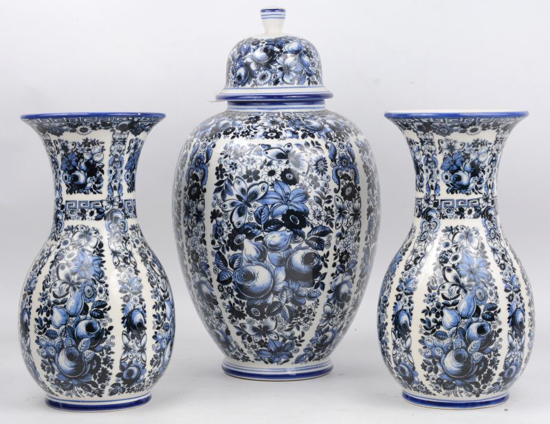 Een driedelig kaststel van Delfts aardewerk met een blauw op wit bloemendecor.