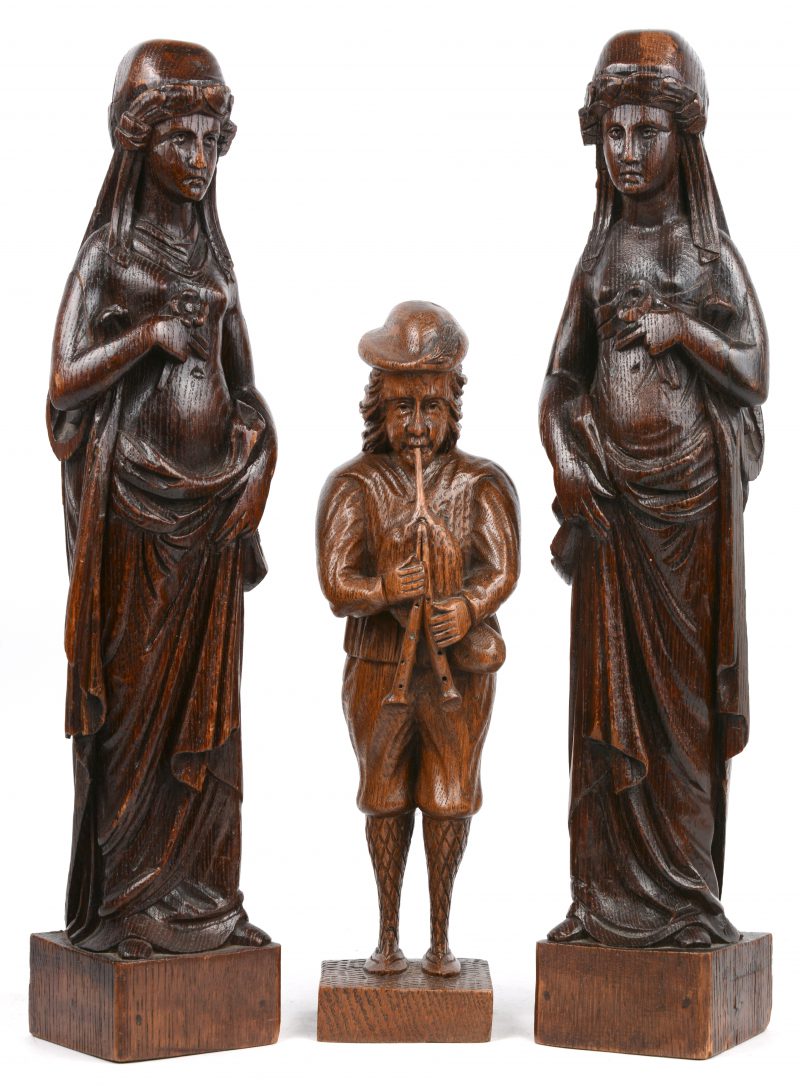 Een lot van drie gesneden houten beelden, bestaande uit een doedelzakspeler en twee damesfirguren, vermoedelijk als meubelornamenten.