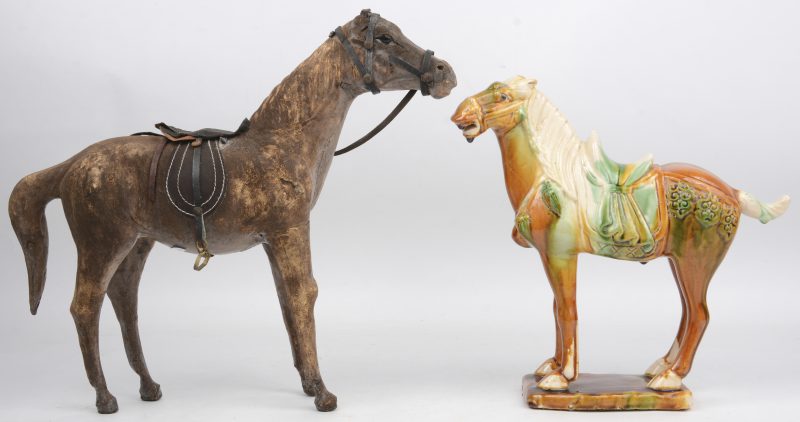 Een lot van twee paardjes, waarbij één bekleed met leder en één van geglazuurd terracotta naar T’ang voorbeeld.