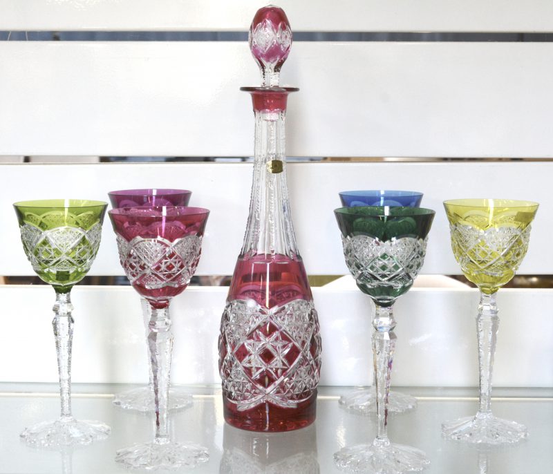 Een reeks van zes glazen van geslepen kristal met kelken in verschillende kleuren. met bijbehorende karaf. Gemerkt.