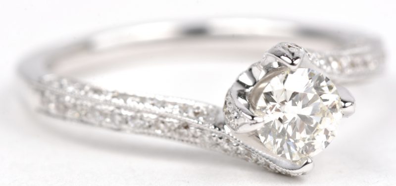 Een 18 K witgouden ring bezet met een centrale briljant van +- 0,50 ct. en briljanten met een gezamenlijk gewicht van +- 0,53 ct.