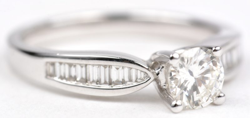 Een 18 K witgouden ring bezet met en centrale briljant van +- 0,49 ct. en briljanten met een gezamenlijk gewicht van +- 0,28 ct.