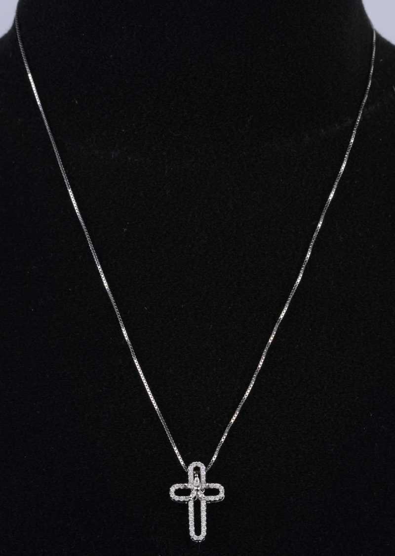 Een 18 K witgouden ketting met hanger in de vorm van een kruis bezet met briljanten met een gezamenlijk gewicht van +- 0,59 ct.