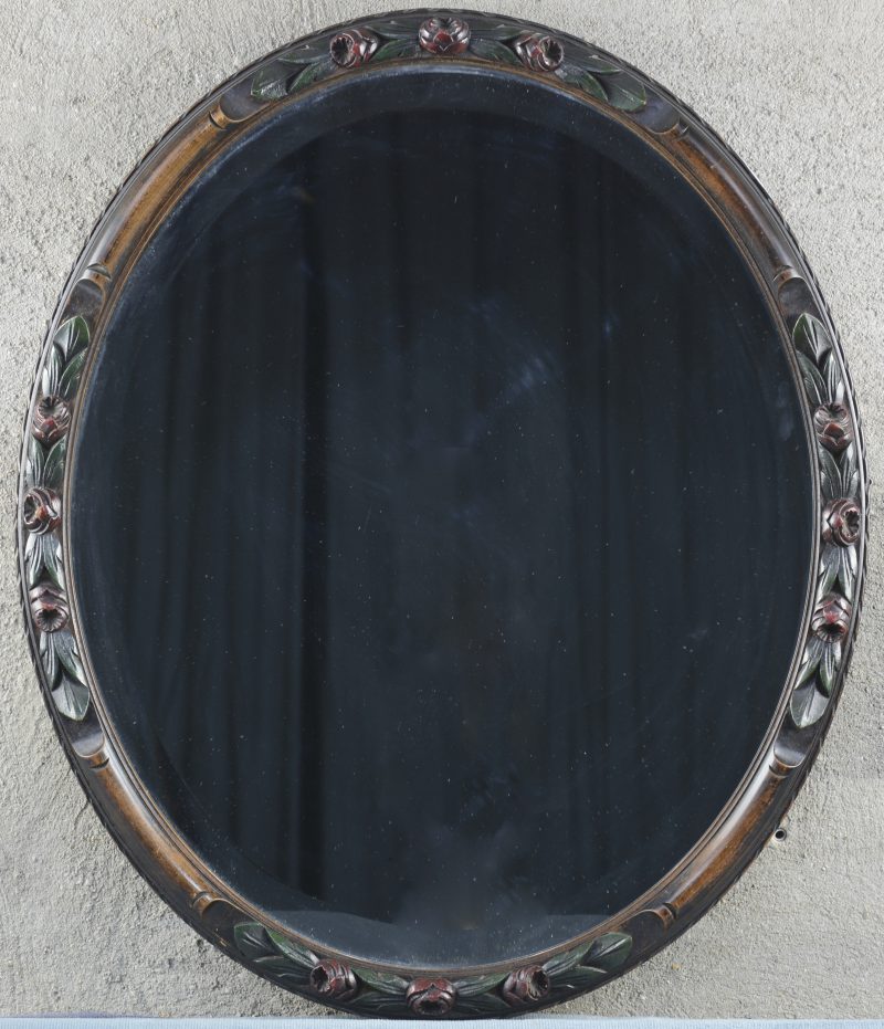 Een ovale spiegel met gebeeldhouwde lijst.