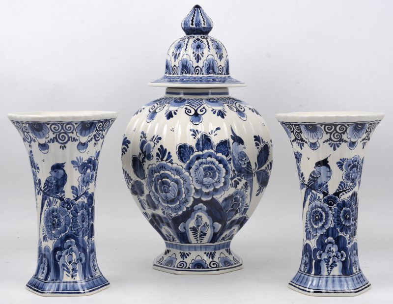 Een driedelig kaststel van Delfts aardewerk met een blauw op wit decor van bloemen en vogels. Onderaan gemerkt ‘LVS’.