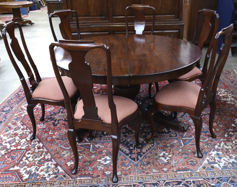 Een verlengbare ronde tafel met zes bijbehorende stoelen van Cubaans mahonie. Gestempeld ‘Tihevdanus Amsterdam op de poot onder het blad.