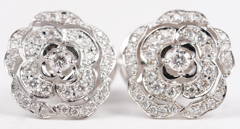 Een paar witgouden bloemvormige oorbellen, model Chanel bezet met briljanten met een gezamenlijk gewicht van +- 0,50 ct.