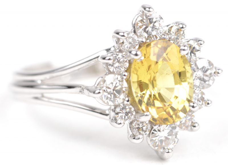 Een 18 K witgouden ring bezet met ovale gele Ceylon saffier van +- 2,17 ct. en briljanten met een gezamenlijk gewicht van +- 1,04 ct.