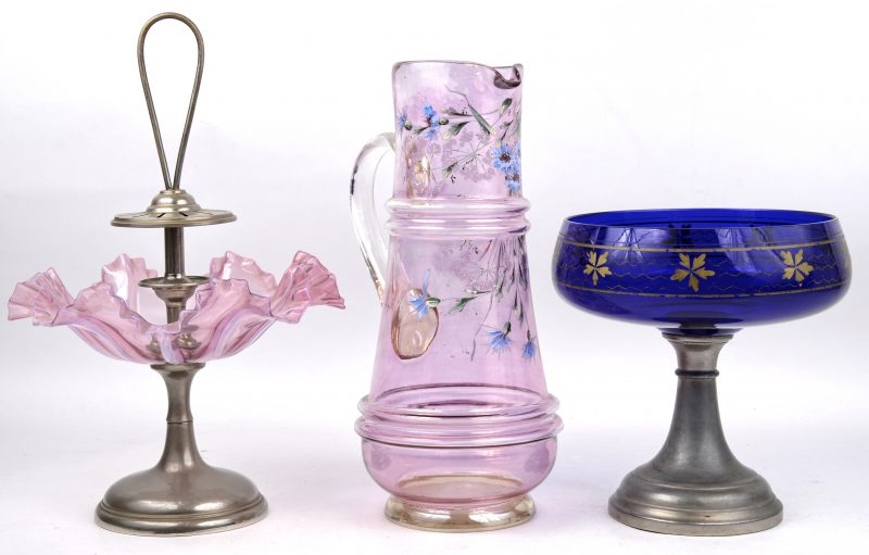 Drie stuks gekleurd glaswerk, bestaade uit een schenkkan, een bonbonschaaltje op voet en een  blauwe coipe op voet met verguld decor.