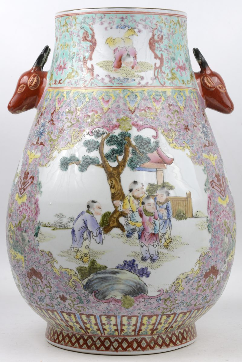 Een vaas van Chinees porselein met een decor van kinderen aan een pruimenboom en met hertenkoppen als handvatten. Onderaan gemerkt.