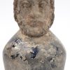 Een antiek glazen kruikje, versierd met een bebaard mannenhoofd van terracotta.