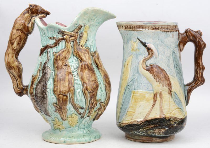 Twee verschillende schenkkannen van meerkleurig aardewerk, versierd met dieren. Eén gemerkt onderaan.