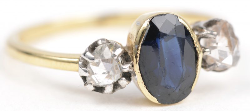 Een 18 K wit en geelgouden ring bezet met twee diamanten oude slijp met een gezamenlijk gewicht van +- 0,30 ct. en een centrale saffier van +- 0,75 ct.