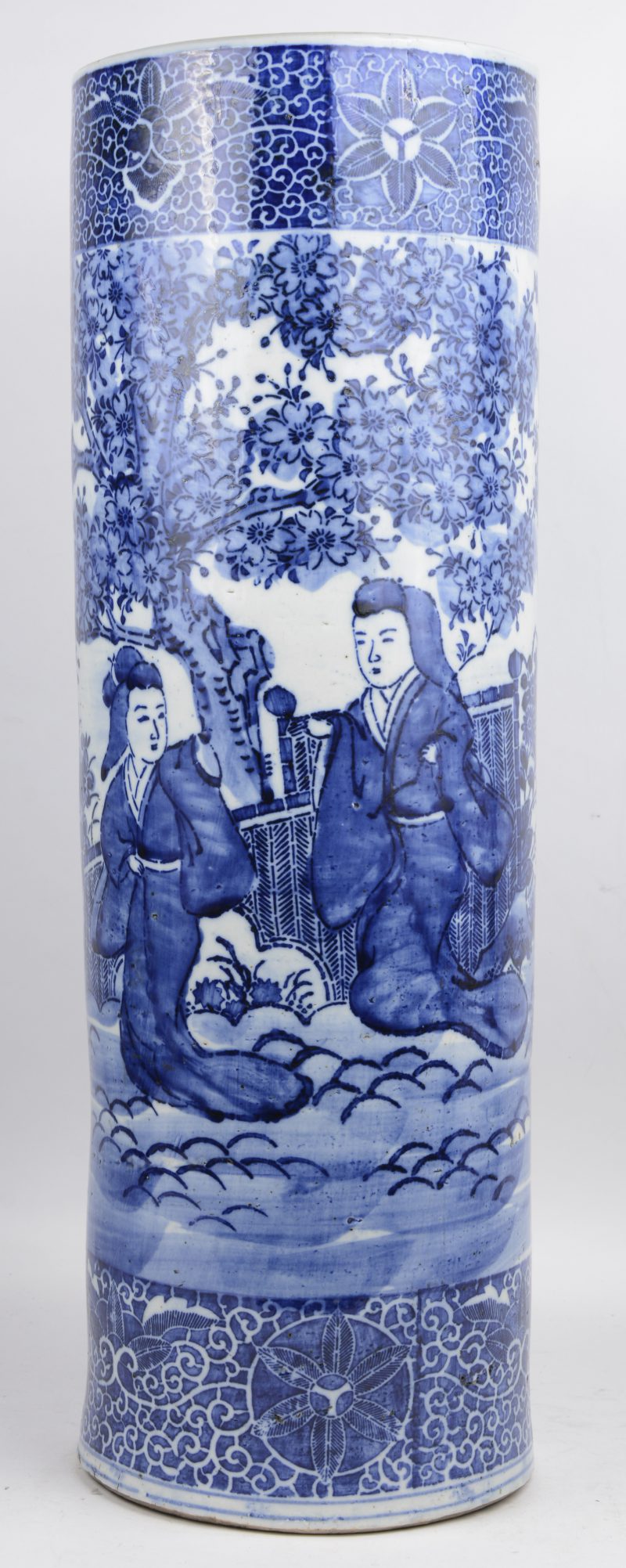 Een cilindrische paraplubak van Japans porselein met een blauw-wit decor van concubines in een tuin. Tijdperk Meiji, omstreeks 1900.