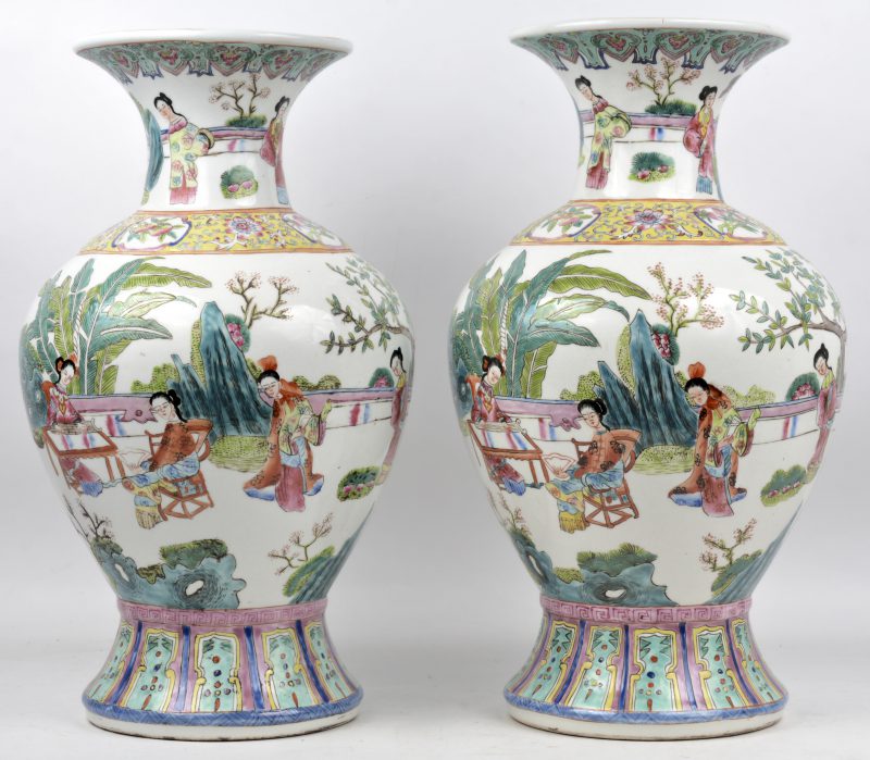 Een paar vazen van Chinees porselein met een decor van personages in een tuin en famille-rose motieven. Onderaan gemerkt.
