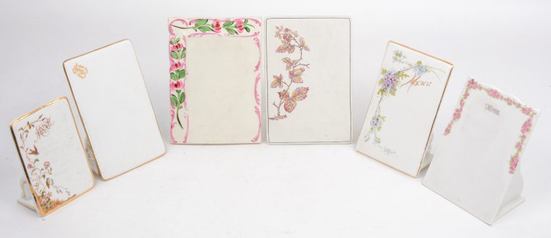 Zes rechthoekige menuhouders van porselein en biscuit versierd met diverse bloemenmotieven, eentje met een monogram, eentje gemerkt van Lunéville, een ander van Parijs. Omstreeks 1900.