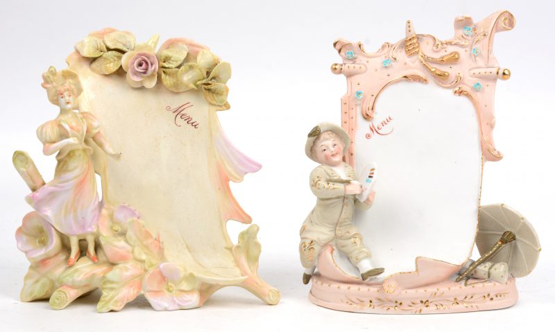 Twee diverse menustaanders van polychroom biscuit en van creamware. Voorstelling van een kleine jongen met een schilderspallet en een jonge vrouw met rozen. Omstreeks 1900.