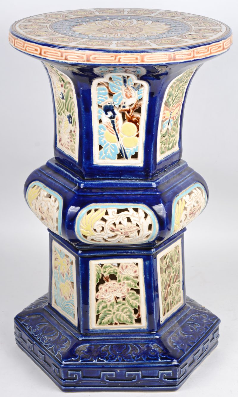 Een piëdestal van opengewerkt aardewerk, versierd met een meerkleurig decor van dieren en bloemen op blauwe fond.