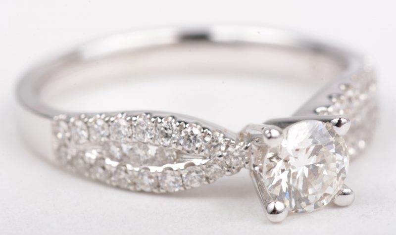 Een 18 K witgouden ring bezet met een centrale briljant van +- 0,51 ct. VVS1 en briljanten met een gezamenlijk gewicht van +- 0,36 ct.