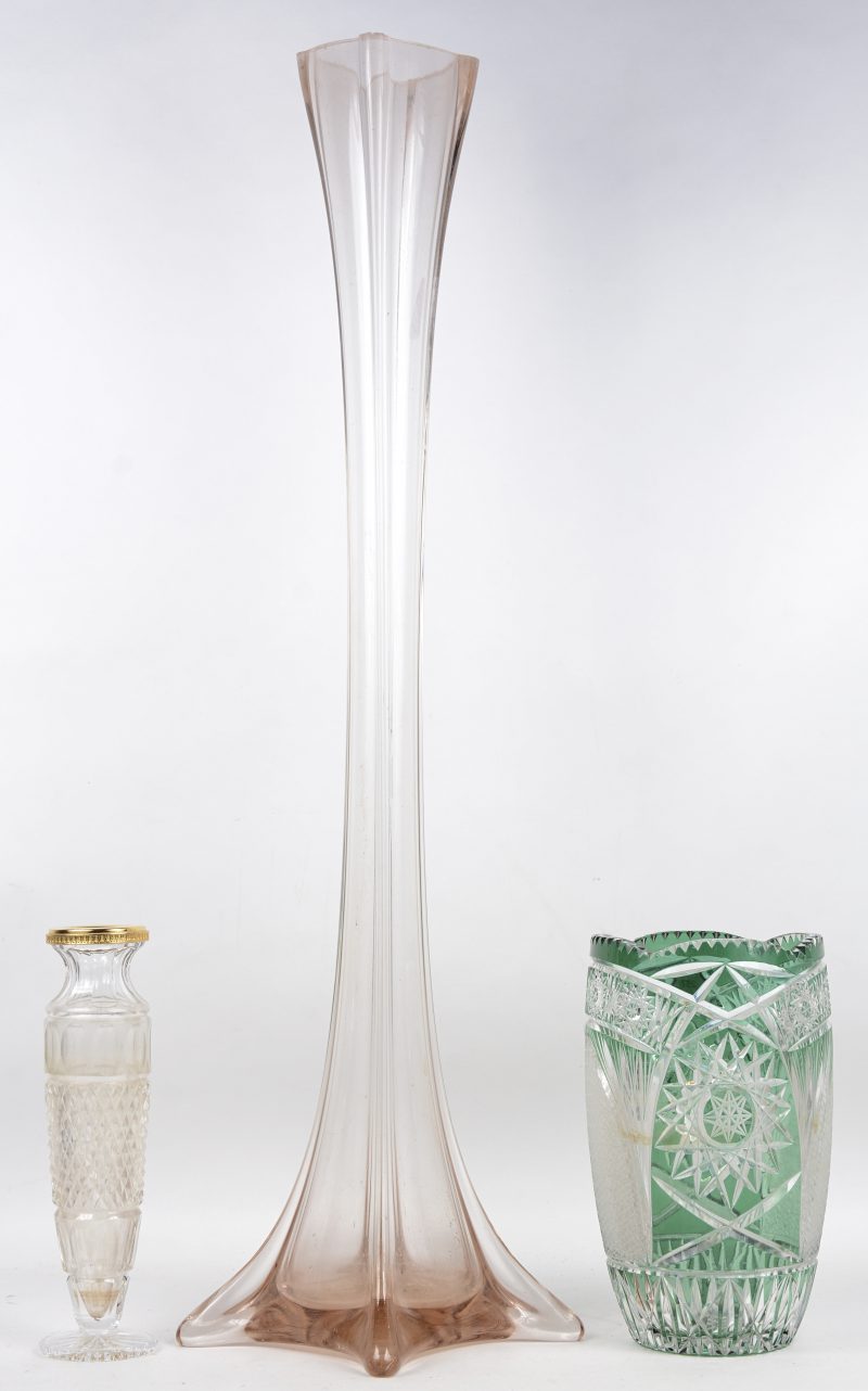 Een lot van drie vazen, bestaande uit een geslepen Boheemse van groen en kleurloos kristal, een kleine kleurloze met messingen montuur en een langerekte vaas van zalmroze glas.