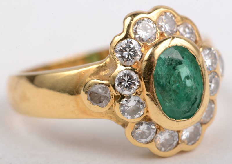 Een 18 K geelgouden ring bezet met briljanten met een gezamenlijk gewicht van +- 0,60 ct. en een centrale  Columbiaanse smaragd van +- 0,60 ct.