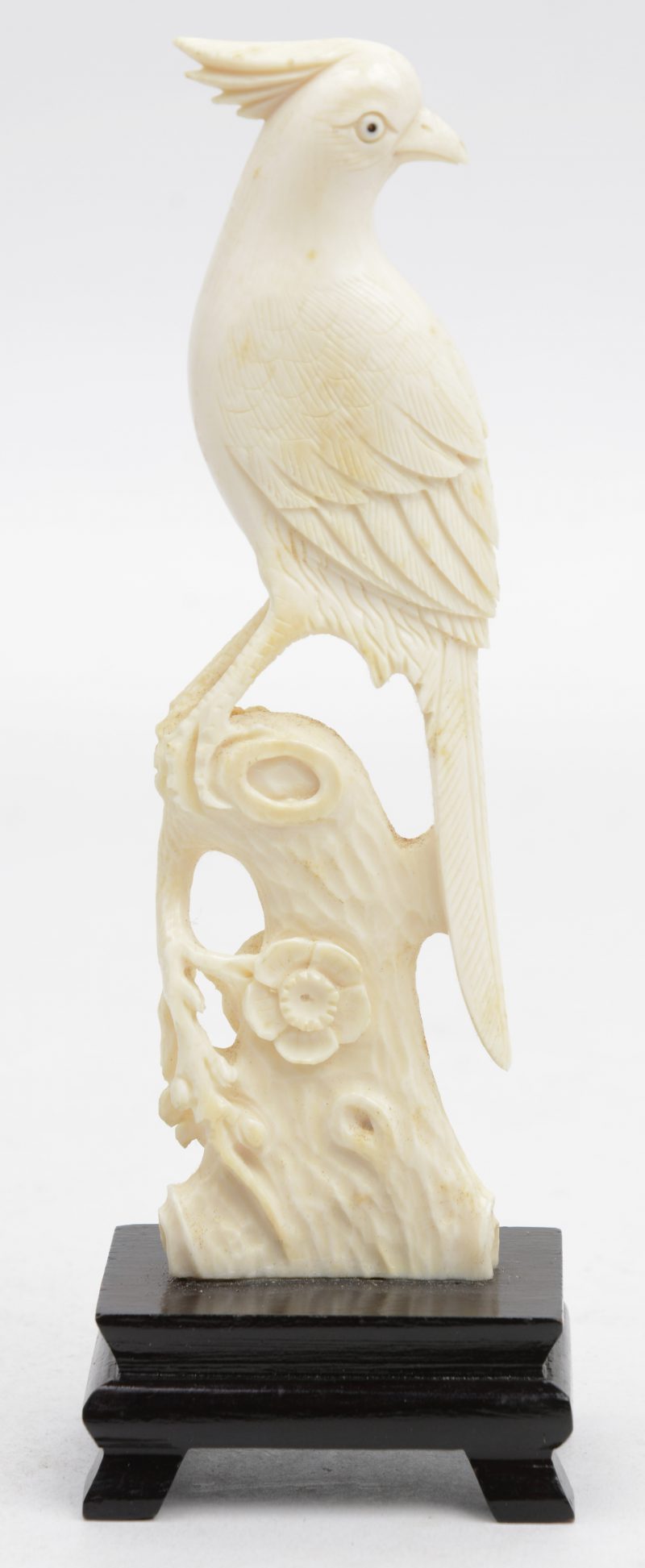 Een vogel van fijn gesneden ivoor op een houten sokkeltje. Chinees werk.