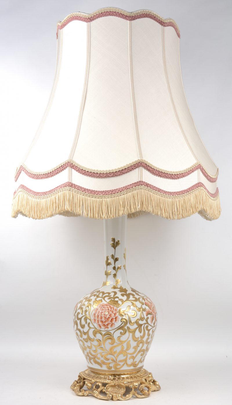 Een porseleinen lampvoet met verguld en meerkleurig bloemendecor in reliëf op verguld bronzen voet. Italiaans werk, gemerkt met apocrief Sèvresmerk.