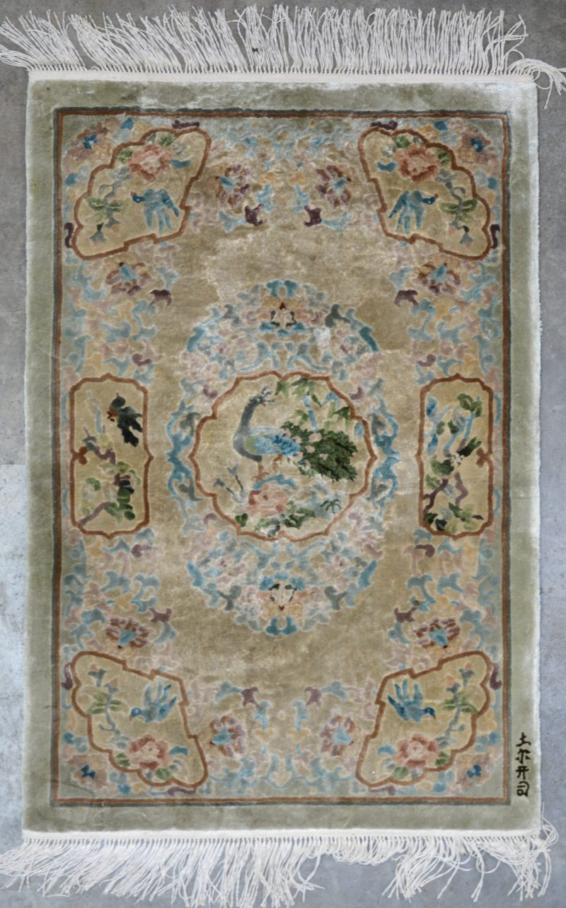 Een handgeknoopt tapijtje van zijde met vogels in het decor. Gesigneerd.