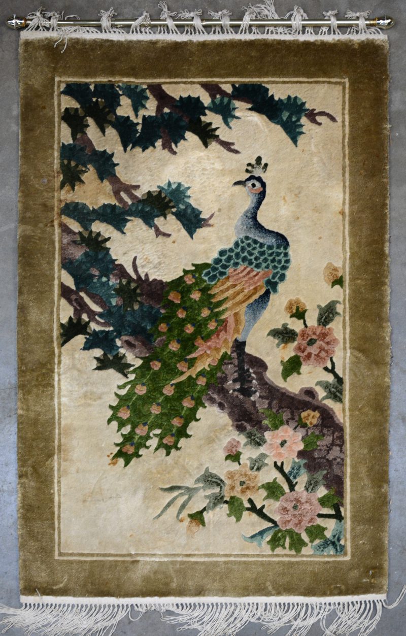 Een klein wandkleedje van zijde met decor van een pauw op een tak.