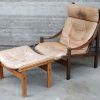 Een paar vintage houten designfauteuils met bijpassende voetbankjes. Met lederen kussens.