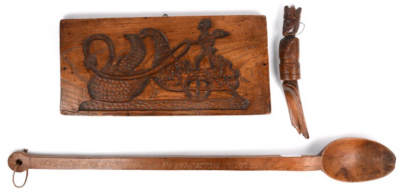 Een lot antiek houtsnijwerk, bestaande uit een speculaasplank, een grote lepel en een gesneden handvat van een schep in de vorm van een vorst met datum 1902.