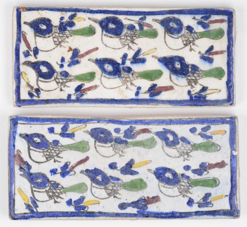 Twee rechthoekige Perzische tegels van polychroom aardewerk met vogeltjesmotief.