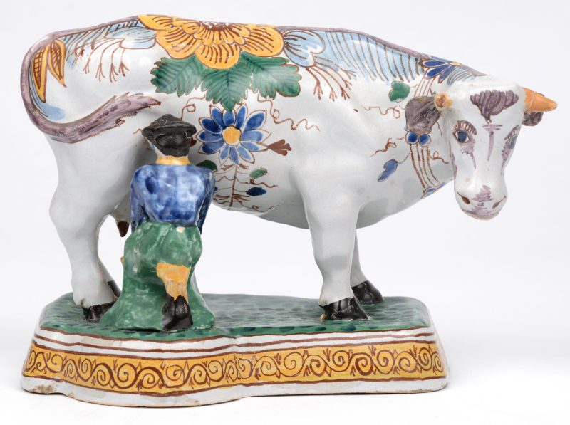 Een koe met boertje van meerkleurig Delfts aardewerk. Onderaan gemerkt. XVIIIe eeuw. Een hoorntje afgebroken.