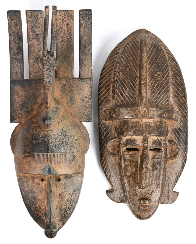 Twee Afrikaanse houten maskers, waarbij één met mesingen beslag.
