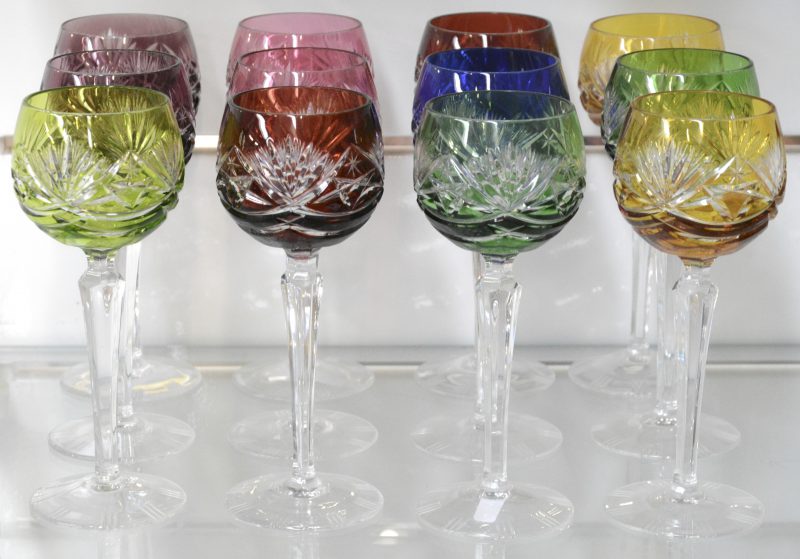 Een reeks van twaalf geslepen kristallen wijnglazen met gekleurde kelken.