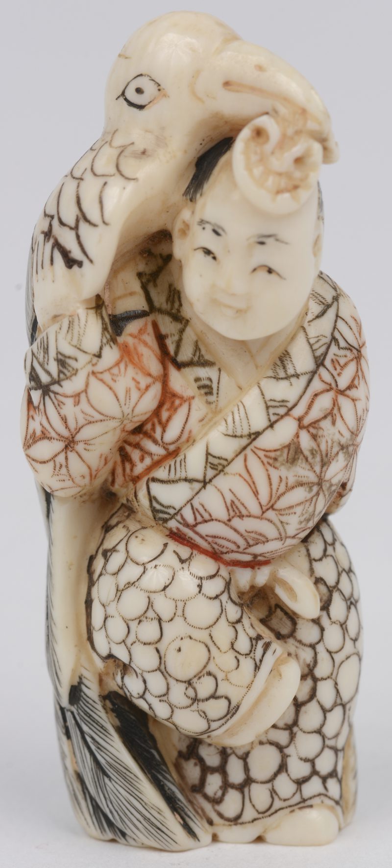 “Man met toekan”. Een fijn gesculpteerde en deels gepolychromeerde ivoren netsuke. Onderaan gesigneerd. Japan, omstreeks 1900.