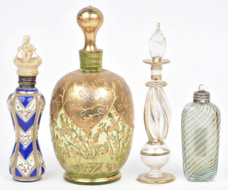 Een lot van vier verschillende parfumflesjes, waarbij één van geslepen glas met handgeschilderd rozendecor en hed deksel met zilveren rand en getooid met fijn gesculpteerd ivoren roeiertje.
