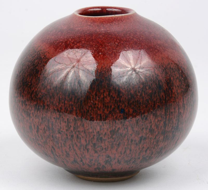 Een bol aardewerken vaasje met gekleurd glazuur.