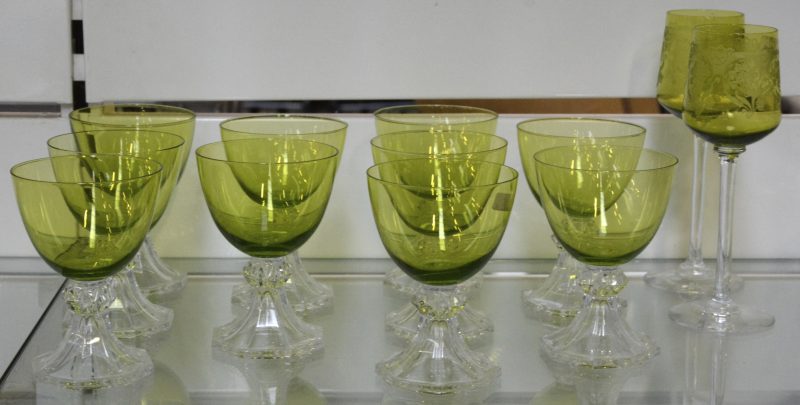 Een reeks van tien kristallen glazen met groene kelk en kleurloze voet. We voegen er twee andere glazen met geslepen groene kelk aan toe.