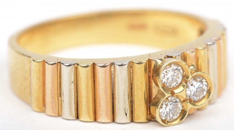 Een ring 18 K in drie kleuren goud bezet met een drie briljanten.