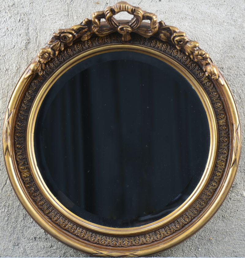 Een ronde spiegel met een kuif versierd met bloemen.