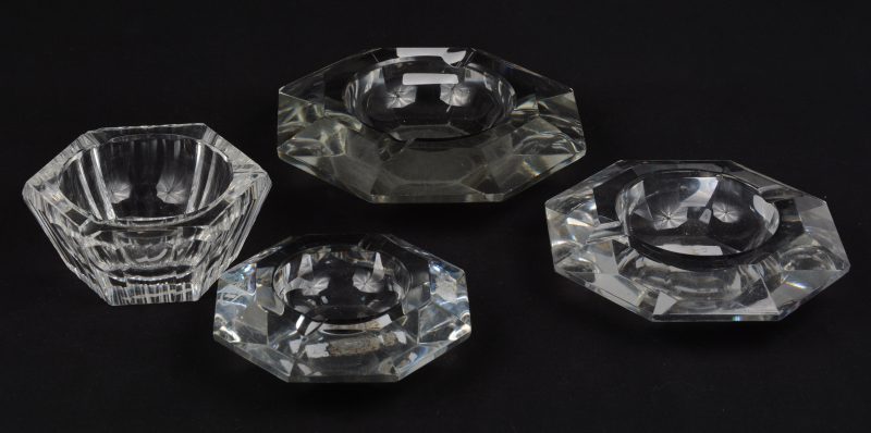 Drie achthoekige asbakken van kleurloos geslepen kristal. Afnemende afmetingen, de grootste zonder merk, de kleinste met een ingeslepen maçoniek embleem. We voegen er een ander, kleiner model aan toe, zeshoekig en gemerkt.