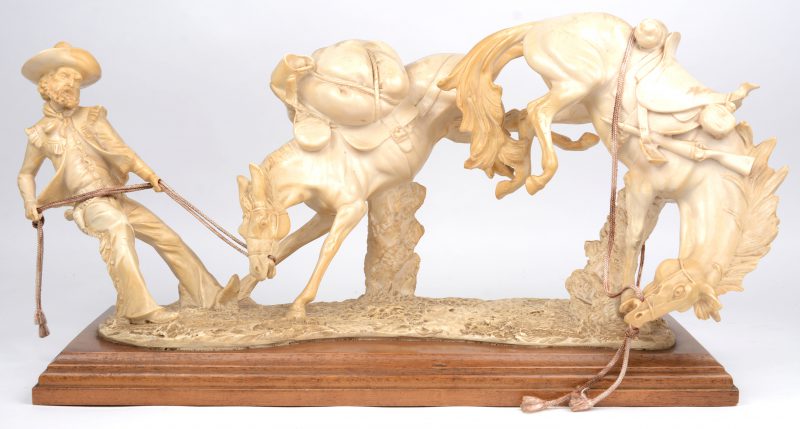 “Cowboy met bokkende paarden”. Een Italiaanse kunststof groep op houten sokkel. Naar ontwerp van A. Santini.