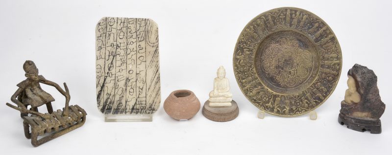 Een lot bestaande uit een Turks schaaltje van koper, een aardewerken potje, een albasten plaquette met inscripties, een kleine ivoren Boeddha, een metalen beeldje van een muzikant uit Benin en een Chinees beeldje van speksteen.