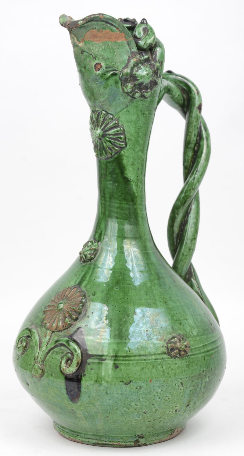 Een antieke aardewerken schenkkan met groen glazuur. Tuit gerestaureerd.
